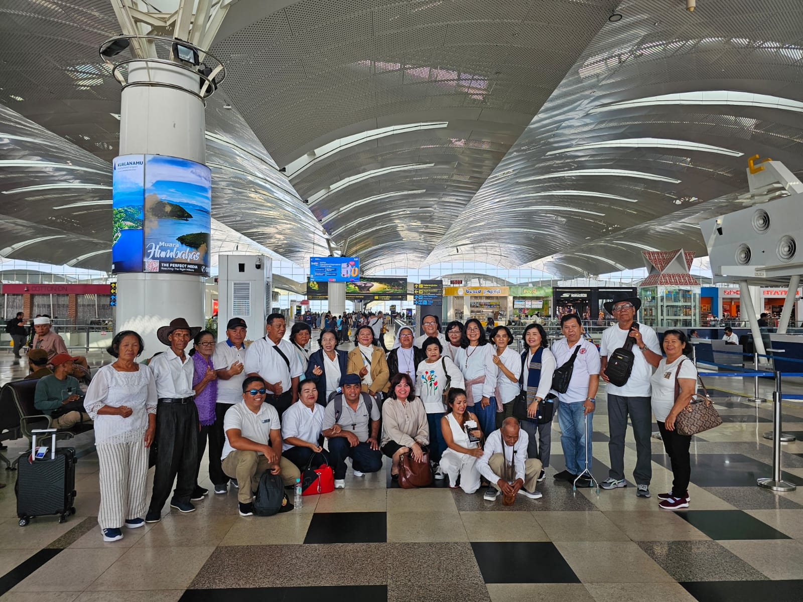 Rombongan Okdo Tours di bandara dengan spanduk keberangkatan